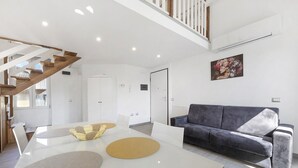 A modern living space with a staircase, a sofa, and a dining area. - Apartment 'Silver' with Wi-Fi and Air Conditioning (Delebio)