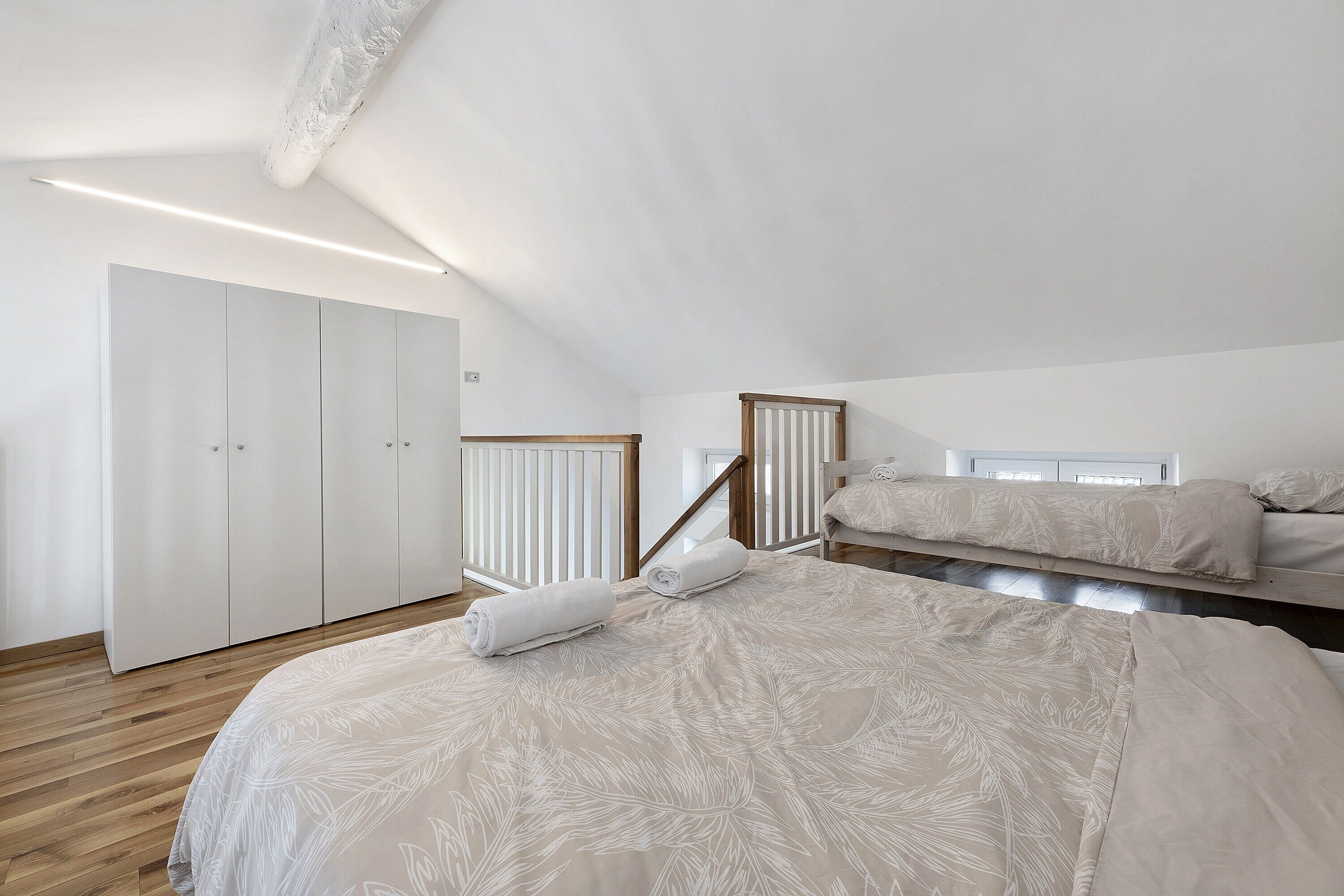 Ein Schlafzimmer mit einem großen Bett, einem Kleiderschrank und einem Fenster mit Jalousien.