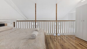 A bedroom with a wooden floor, a bed with a rolled towel, a white wardrobe, and a window with blinds. - Apartment 'Silver' with Wi-Fi and Air Conditioning (Delebio)
