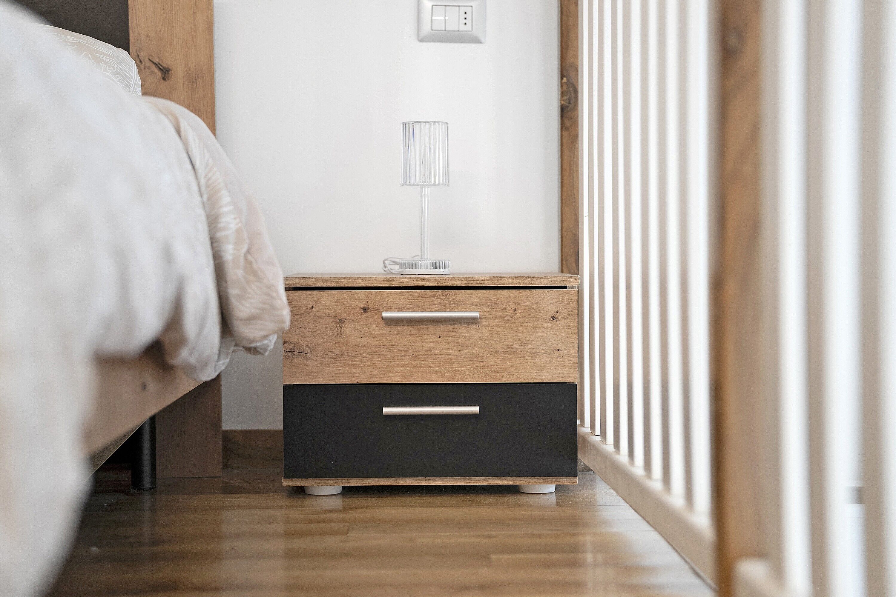 Une chambre à coucher avec une table de chevet en bois, une lampe et un lit.