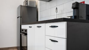 A kitchen with a black countertop, white cabinets, and a coffee machine. - Studio Apartment 'Monolocale Red' with Wi-Fi and Air Conditioning (Delebio)
