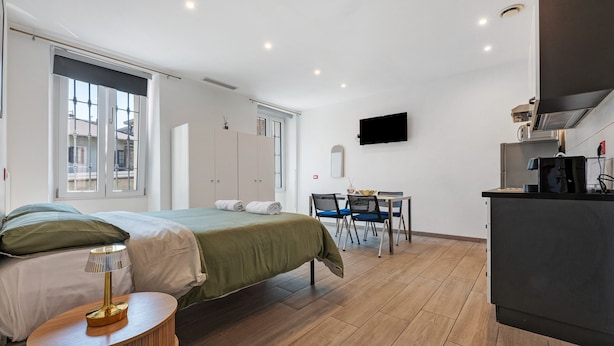 A modern hotel room with a bed, bedside table, desk, chairs, and a kitchenette. - Studio Apartment 'Monolocale Red' with Wi-Fi and Air Conditioning (Delebio)