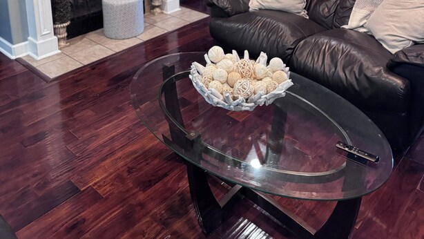 A living room with a fireplace, a leather sofa, a glass coffee table, and a TV mounted on the wall. - Creative Heart - Get Away!!   Spacious 4BR/3 Full Bath Home for your Enjoyment. (Gulfport)
