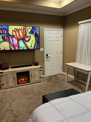 Une chambre avec une télévision, une cheminée, un lit et une porte.