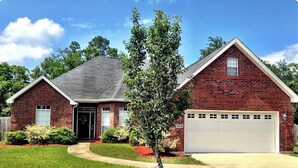 A two-story brick house with a garage, a front door, and a small tree in the front yard. - Creative Heart - Get Away!!   Spacious 4BR/3 Full Bath Home for your Enjoyment. (Gulfport)