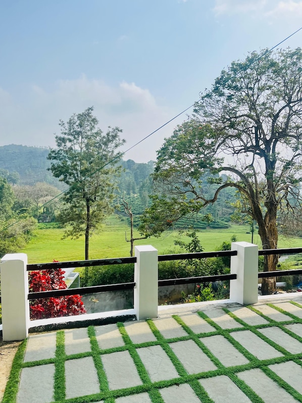 Un balcón con vistas a un paisaje verde, un árbol y una barandilla blanca.