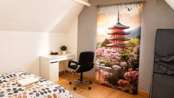 Une chambre à coucher comprenant un lit, un bureau, une chaise et une grande fenêtre donnant sur une pagode japonaise traditionnelle.