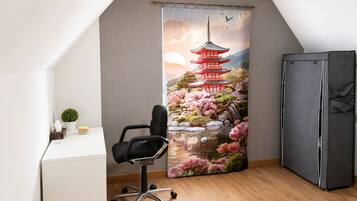 Una habitación con un escritorio, una silla de oficina negra, un cuadro grande de una pagoda y un armario.