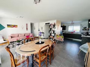 Un salon moderne comprenant une table à manger, un canapé et un coin cuisine avec une fenêtre.