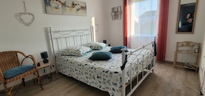 Une chambre à coucher avec un lit, une chaise, une petite table et un miroir.
