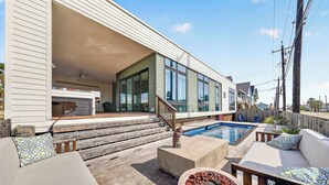 A modern house with a covered patio, outdoor seating, a pool, and a fireplace. - Resting Beach Face | Private Pool • Modern Coastal Retreat • Prime 11th St Location (Port Aransas)