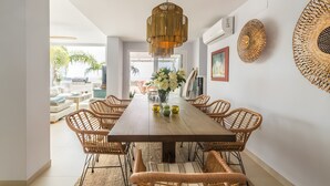 A dining area with a long wooden table, wicker chairs, and a hanging light fixture. - Villa 'Los Altos' with Sea Views, Wi-Fi, and Air Conditioning (Almuñécar)