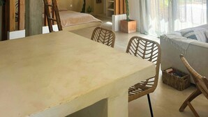 Un espace repas comprenant une table, des chaises, un luminaire suspendu et une échelle appuyée contre un mur.