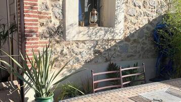 A patio with a tiled table and chairs, a potted plant, and a stone wall.
