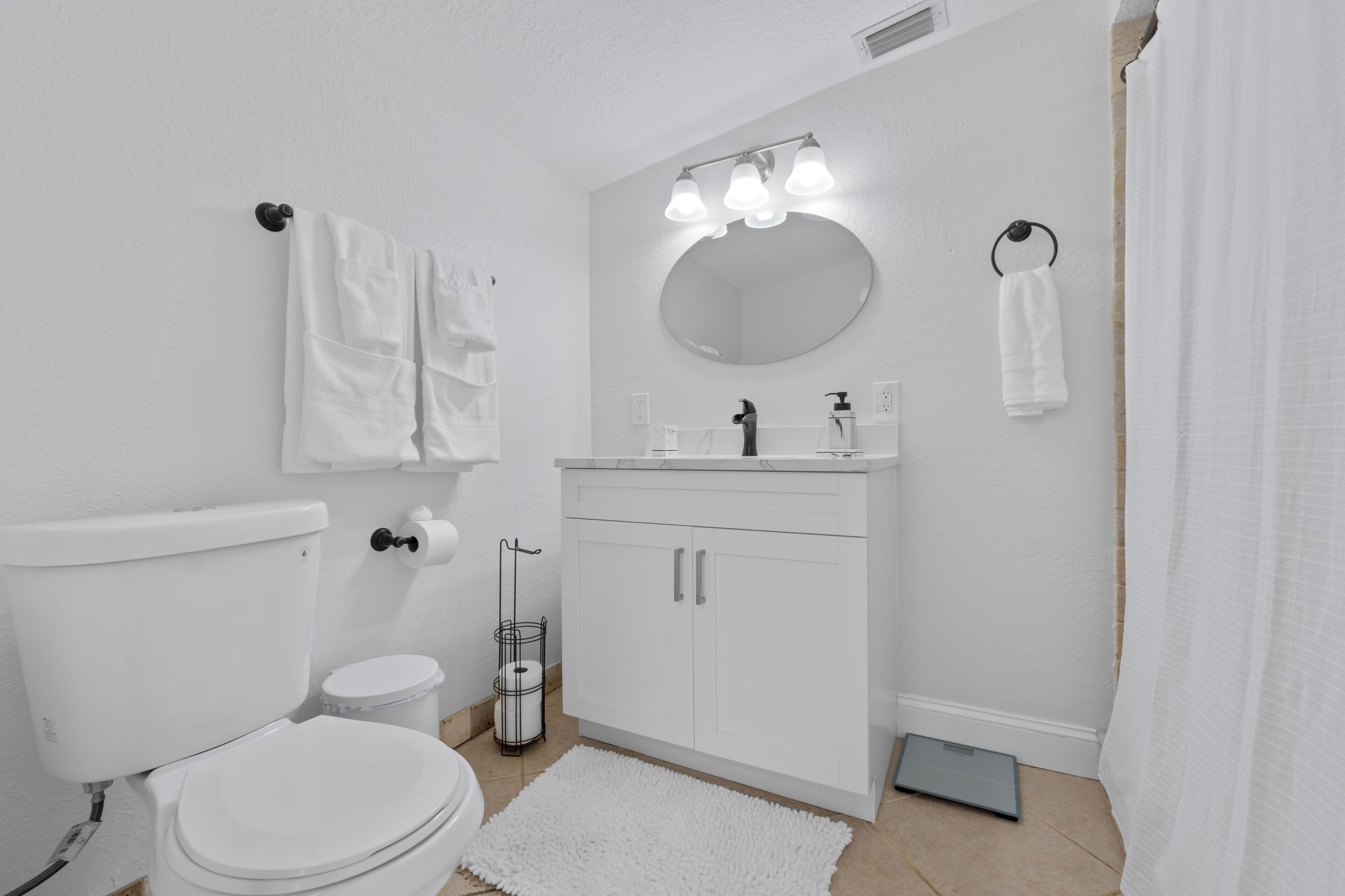 Une salle de bain moderne équipée de toilettes, d’un lavabo, d’un miroir et d’un porte-serviettes.