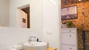 A bathroom with a white sink, mirror, and a brick wall.