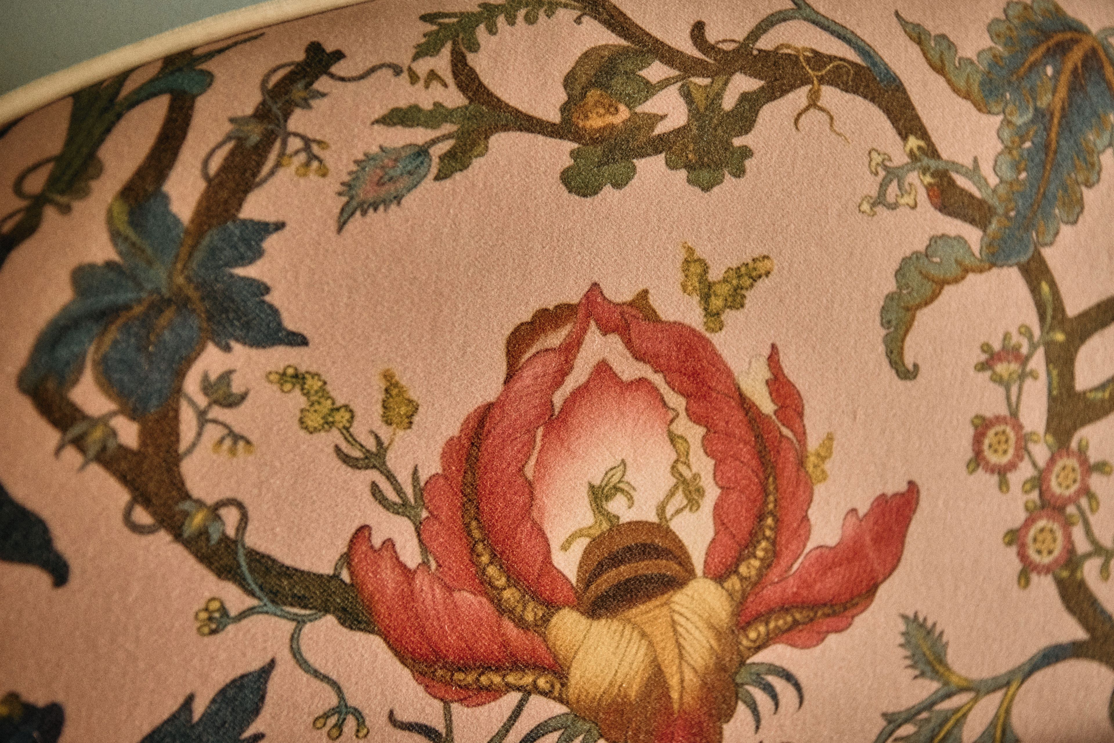 A close-up of a fabric with a floral pattern, including a prominent red flower and green foliage.