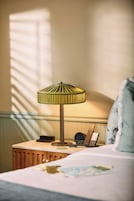 A hotel room with a bed, a bedside table with a lamp, a telephone, and a clock.