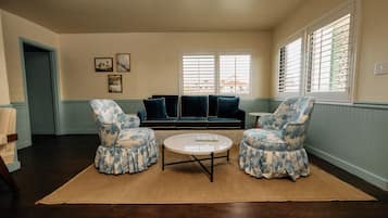 A living room with a sofa, two armchairs, a coffee table, and a rug.