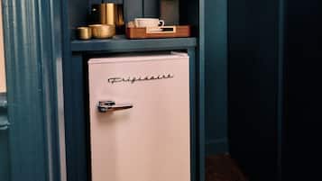 A compact kitchenette with a white refrigerator, a coffee maker, and a small wooden box on top.