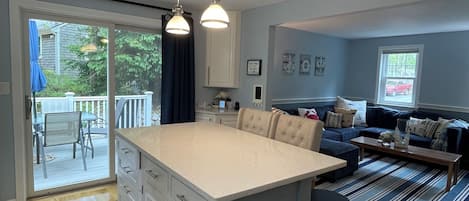 Une cuisine moderne dotée d’un grand îlot central, un coin repas avec une table et des chaises, et un espace salon avec un canapé et une table basse.