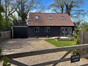 A lodge with a tiled roof, a black exterior, and a gravel driveway. - Ash Tree Lodge (Norwich)