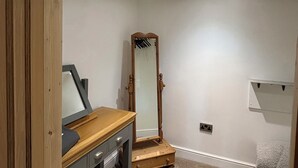 Ein Zimmer mit einem Holzschrank, einem großen Spiegel und einer weißen Wand mit Steckdose.