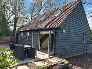 A house with a patio, outdoor furniture, and a sliding glass door leading to an interior space. - Ash Tree Lodge (Norwich)