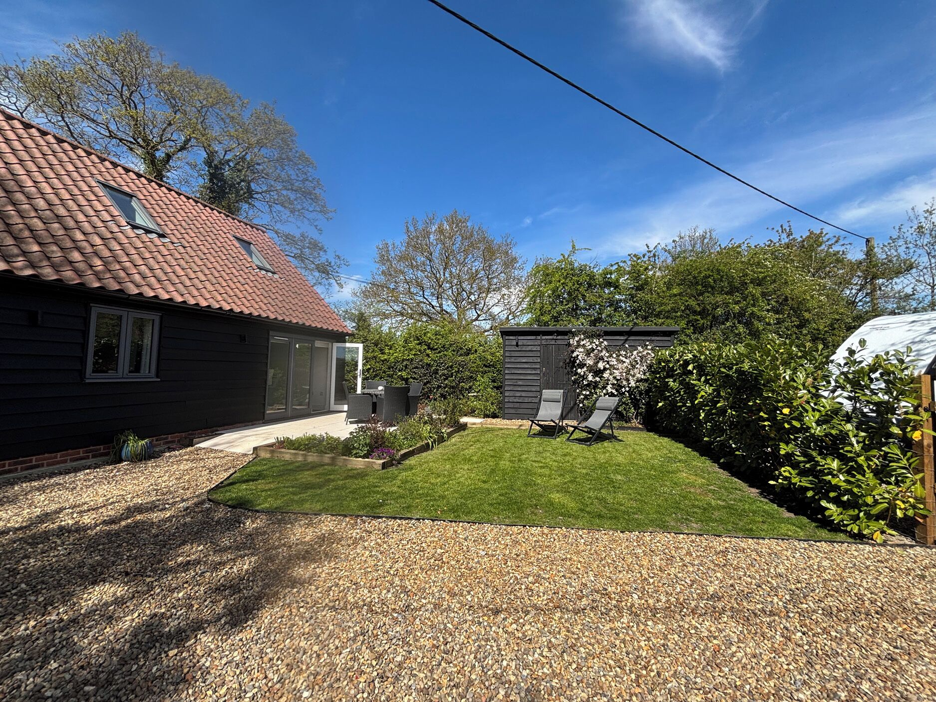 A house with a red-tiled roof, a covered outdoor seating area, and a well-maintained lawn.