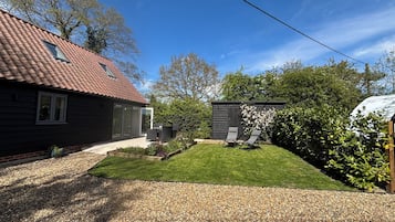A house with a red-tiled roof, a covered outdoor seating area, and a well-maintained lawn.