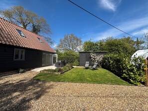 Ein Haus mit rotem Ziegeldach, einer überdachten Terrasse und einem gepflegten Rasen.
