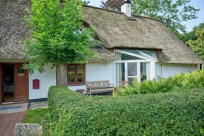 A traditional thatched-roof house with a bench, a mailbox, and a window. - Charming country house in Schleswig-Holstein (Fedderingen)