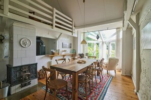 A dining area with a wooden table and chairs, a fireplace, and a view of the outdoors. - Charming country house in Schleswig-Holstein (Fedderingen)