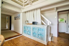 A room with a wooden floor, a white staircase, a blue cabinet with drawers, and a painting on the wall. - Charming country house in Schleswig-Holstein (Fedderingen)