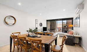 Un salon moderne comprenant un coin repas, un ensemble de canapés, une table basse et une grande fenêtre.