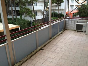 Ein Balkon mit gefliestem Boden, Metallgeländer und einer Klimaanlage.