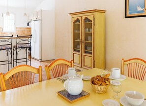 A dining area with a table set for four, chairs, a cabinet with glass doors, and a kitchen in the background. - Fayence Romantic Apartment (Fayence)