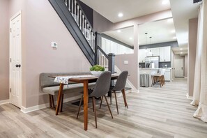 A dining area with a table, chairs, and a staircase. - Luxurious, Modern Duplex | 6 Bedrooms! Sleeps 12+ (Indianapolis)