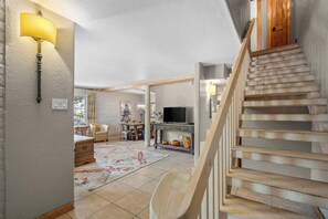 Eine Treppe führt zu einem Wohnbereich mit einem Fernseher, einem Holzstuhl und einer Lampe.