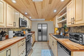 Eine Küche mit Holzausstattung, einem Edelstahlkühlschrank, einer Mikrowelle, einem Herd, einem Toaster und einem Geschirrspüler.