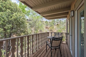 Eine Holzterrasse mit Tisch und Stühlen mit Blick auf eine gebirgige Landschaft.