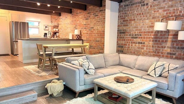 Ein modernes Wohnzimmer mit einer Eckcouch, einem Couchtisch und einem Essbereich mit Tisch und Stühlen.