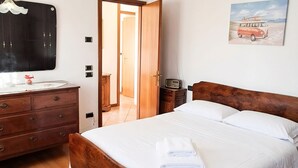 Una camera da letto con un letto di legno, una cassettiera, una toeletta con specchio, una radio e un quadro a tema spiaggia.