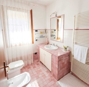Casa de banho com sanita, lavatório e zona de duche.