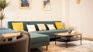 Un salon avec un canapé vert, des coussins jaunes et blancs, une table basse et un tapis moelleux.