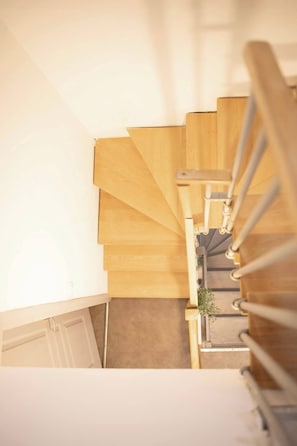 A wooden staircase with a handrail, leading to a lower level.