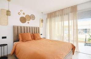 A modern bedroom with a large bed, a bedside table, and a view of the outside. - Dar Yanis -(2-4 Guests) -Beach on foot - A/C - Terrace - Parking - 2 Netflix TVs (Imi Ouaddar)