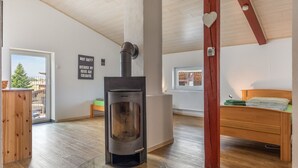 Una habitación con estufa de leña, una cama, una ventana y vistas al exterior.