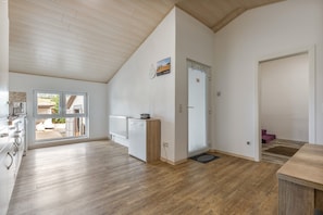 A spacious kitchen with wooden flooring, a built-in oven, and a window overlooking a garden.