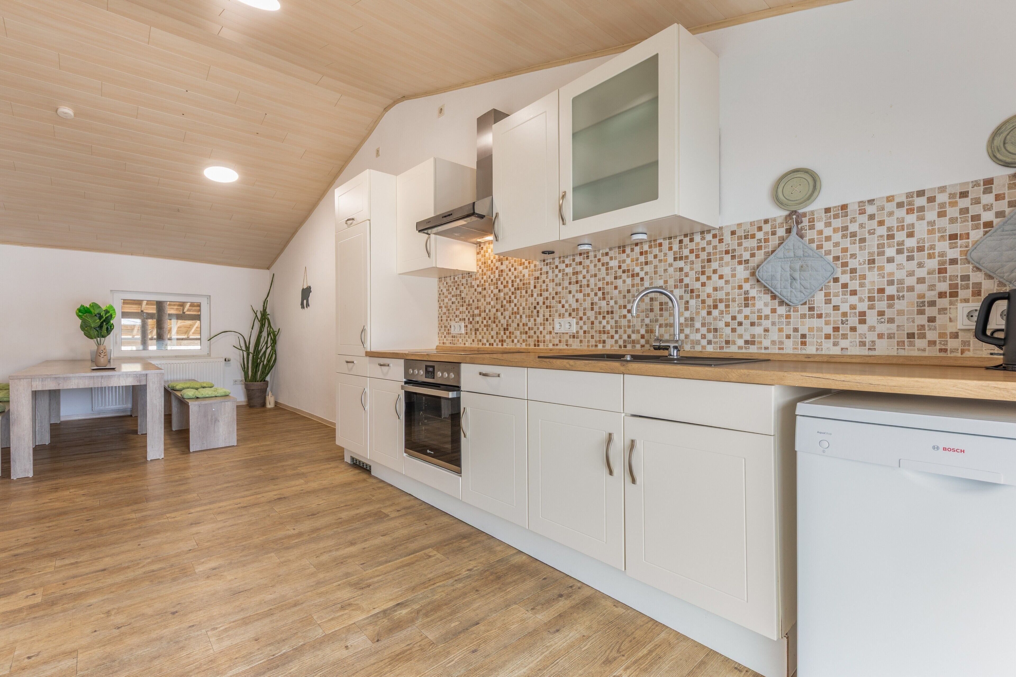 Une cuisine moderne avec des meubles blancs, un plan de travail en bois et un revêtement mural en carreaux.